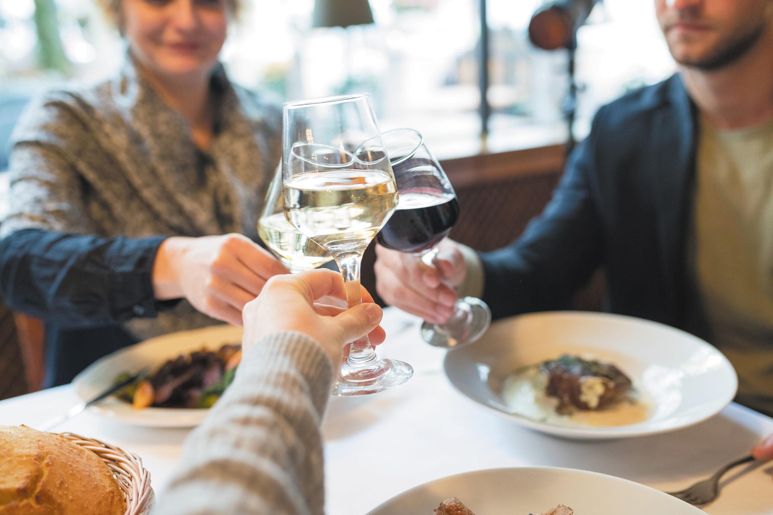 A group of friends toasts wine glasses after dinner