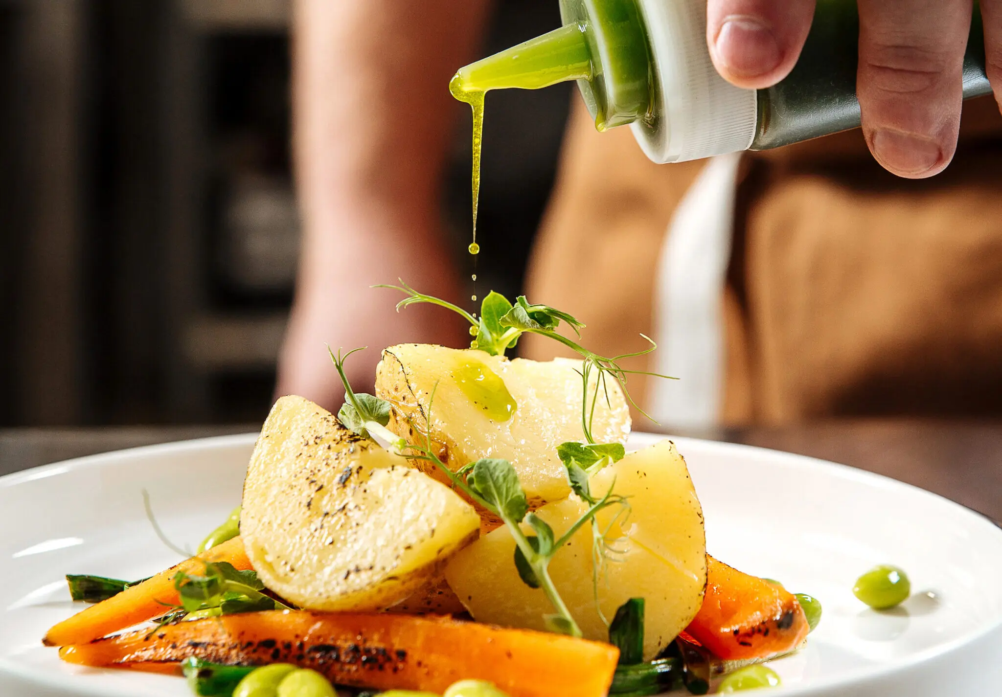 Chef pouring gourmet healthy dish with green sauce
