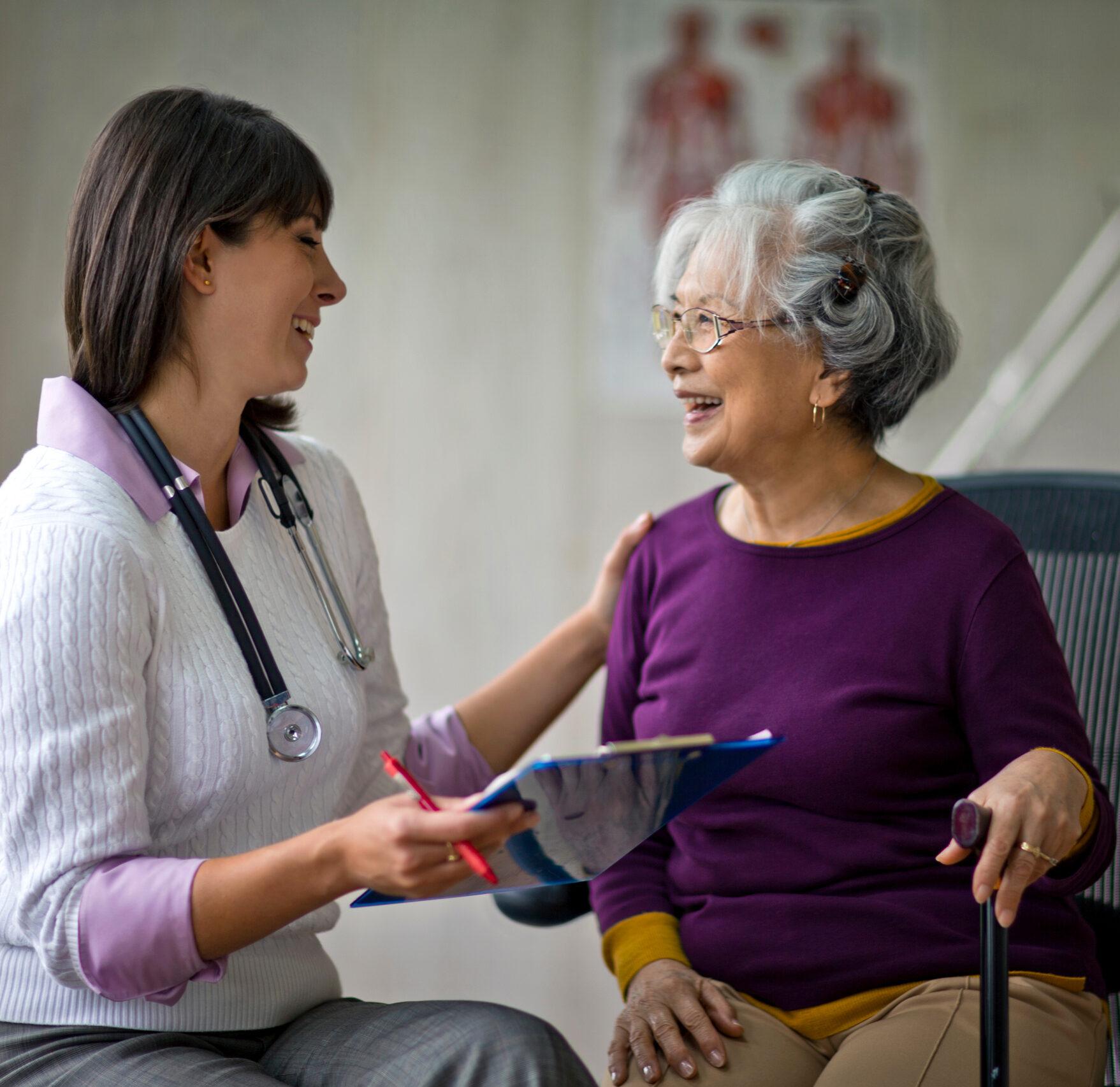 An older woman smiles at a checkup with her doctor.